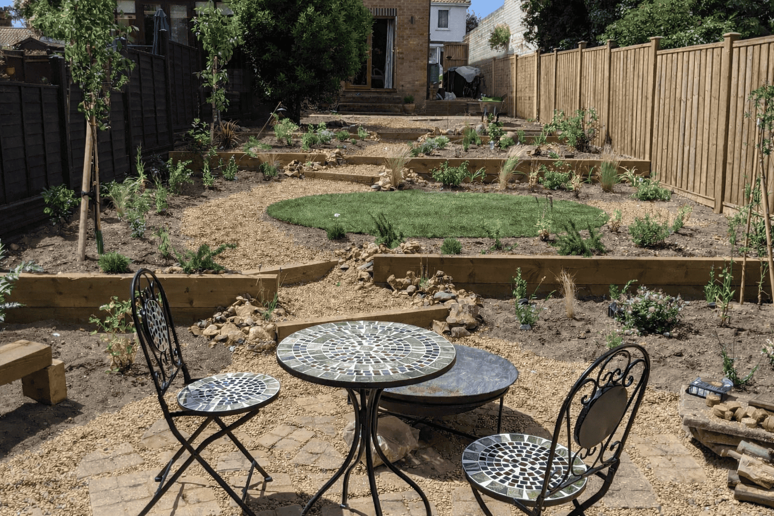 Norwich-terraced-garden-after-installation The newly terraced garden showing the seating area and lawn with sleeper steps